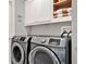 Bright laundry room featuring front-loading washer and dryer, built-in cabinets, and ample storage space at 398 Lake Amberleigh Dr, Winter Garden, FL 34787