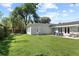 Expansive backyard with manicured green lawn, stone patio, outdoor dining set, and mature shade trees at 420 Sylvan Dr, Winter Park, FL 32789