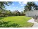 Spacious backyard with lush green grass, a stone patio set, manicured hedges, and beautiful shade trees at 420 Sylvan Dr, Winter Park, FL 32789