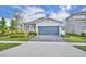 Charming single-story home boasts a well-manicured lawn, paver driveway, and a modern blue garage door at 4426 Davos Dr, Clermont, FL 34711