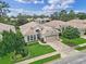 An aerial view showcases the house with mature trees, manicured lawns, and tile roof in a friendly neighborhood at 501 Sotheby Way, Debary, FL 32713