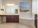 Bright bathroom features a soaking tub with a marble surround and a dark wood vanity with a large mirror at 713 Duff Dr, Winter Garden, FL 34787