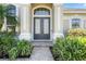 Elegant home entryway with double doors, lush landscaping, and brick paver walkway at 713 Duff Dr, Winter Garden, FL 34787