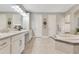 Well-lit bathroom showcasing a soaking tub, double sinks, granite countertop, and updated fixtures at 8718 Shimmering Pine Pl, Sanford, FL 32771