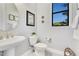 Bright powder room with a stylish pedestal sink, toilet, and decorative artwork at 8718 Shimmering Pine Pl, Sanford, FL 32771