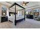 Spacious main bedroom featuring a four-poster bed, plush carpet, and multiple windows for ample natural light at 8718 Shimmering Pine Pl, Sanford, FL 32771