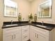 Bathroom with double vanity featuring modern mirrors, dark countertops, and white cabinets at 938 S Bumby Ave, Orlando, FL 32806