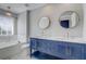 Bathroom with a blue double vanity, marble countertop, and a soaking tub at 13046 Island Breeze Ct, Orlando, FL 32824