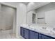 Bathroom featuring a blue double vanity, marble countertop, and a shower at 13046 Island Breeze Ct, Orlando, FL 32824