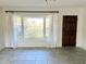 Bright living room features large windows with white curtains, a dark wood door, and neutral tile flooring at 161 Randia Dr, Orlando, FL 32807