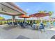 Poolside patio seating area with tables and chairs, featuring shaded umbrellas and palm trees in the background at 1648 Badger Creek Rd, Kissimmee, FL 34744