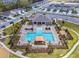 Aerial view of the community pool area with lounge chairs, tables and umbrellas, clubhouse, and parking at 168 Victoria Oaks Blvd, Deland, FL 32724