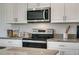 Close-up shot of a modern kitchen featuring stainless steel appliances, white cabinets, and granite countertops at 1861 Walnut Creek Dr, Kissimmee, FL 34744