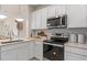 Well-lit kitchen with stainless steel appliances, white cabinets, and a stylish countertop at 2526 Winsome Way, Davenport, FL 33896