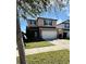 Two-story tan home with a two-car garage and a well-manicured lawn at 3566 Southern Cross Loop, Kissimmee, FL 34744