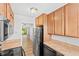 Galley kitchen featuring wood cabinets, laminate countertops, stainless steel appliances, and wood-look flooring at 4312 Lake Underhill Rd # 19, Orlando, FL 32803