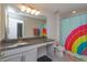 Bright bathroom features granite counters, rainbow shower curtain, and modern fixtures at 5142 Sage Cedar Pl, Sanford, FL 32771