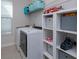 A full-size washer and dryer, with storage shelves, in a modern laundry room at 5142 Sage Cedar Pl, Sanford, FL 32771