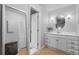 Bright bathroom featuring wood floors, a circular mirror, and white vanity with plenty of storage at 611 Aldama Ct, Ocoee, FL 34761