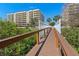 A bridge leading to a beachfront condominium complex with palm trees under a clear sky at 6336 Buford St # 706, Orlando, FL 32835