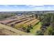 Aerial view of the property with agriculture plots and blue warehouse under a sunny sky at 8122 Pine Island Rd, Clermont, FL 34711