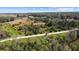 Aerial view of property with trees, grass, a dirt road, and surrounding buildings in the distance at 8122 Pine Island Rd, Clermont, FL 34711