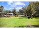 A lush backyard featuring a well-manicured lawn with a wheelbarrow and structures at 8122 Pine Island Rd, Clermont, FL 34711