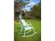 A set of white rocking chairs placed on a green lawn, inviting relaxation and comfort at 8122 Pine Island Rd, Clermont, FL 34711