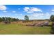 Exterior view of the property with agriculture plots under a sunny sky with scattered clouds at 8122 Pine Island Rd, Clermont, FL 34711