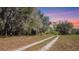 Scenic property view showcasing peaceful dirt path in a field, creating a serene atmosphere at sunset at 8122 Pine Island Rd, Clermont, FL 34711