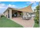 Beautiful outdoor patio with ample seating, a shade sail, and lush landscaping, ideal for gatherings and relaxation at 10139 Grande Loop, Clermont, FL 34711