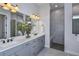 Contemporary bathroom featuring double sinks, large vanity, frameless shower, gray tiles, and modern lighting at 1593 Evening Summit Cir, Minneola, FL 34715