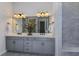 A stylish bathroom featuring double sinks, gray cabinets, a large mirror, and modern pendant lighting at 1593 Evening Summit Cir, Minneola, FL 34715