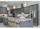 Modern kitchen with gray cabinets, stainless steel appliances, island with seating and three pendant lights at 1593 Evening Summit Cir, Minneola, FL 34715