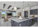 Gray island kitchen open to the living room with breakfast bar, stylish pendants and wood beam ceiling at 1593 Evening Summit Cir, Minneola, FL 34715