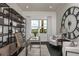 A sunlit home office featuring custom shelving, comfortable seating, and a large clock creating an inspiring workspace at 1593 Evening Summit Cir, Minneola, FL 34715