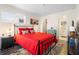 Bright bedroom boasts a plush red quilt, hardwood floors, and light-filled ambiance at 1601 E 1St Ave, Mount Dora, FL 32757
