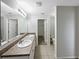 Neutral bathroom featuring double sinks, vanity, tile floors and an open door to a walk-in closet at 1613 Reflection Cv, St Cloud, FL 34771