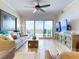 Bright living room with tile floors, ceiling fan, and sliding glass doors to ocean view balcony at 1705 S Atlantic Ave # 402, New Smyrna Beach, FL 32169