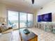Sunlit living room with tile floors, sliding glass doors to balcony, and stylish TV console at 1705 S Atlantic Ave # 402, New Smyrna Beach, FL 32169