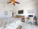 Comfortable bedroom with mounted TV, tiled floors, and dedicated workspace at 1705 S Atlantic Ave # 402, New Smyrna Beach, FL 32169