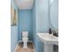 Charming half-bathroom with a pedestal sink, round mirror, and refreshing blue paint at 1856 Cross Prairie Pkwy, Kissimmee, FL 34744