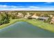 Aerial view of homes with well-maintained lawns and a serene lake as a backdrop in a peaceful neighborhood at 1950 Windward Oaks Ct, Kissimmee, FL 34746