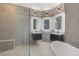 Bathroom featuring a glass enclosed shower, gray tiling and dual floating vanities with illuminated mirrors at 1950 Windward Oaks Ct, Kissimmee, FL 34746
