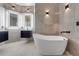 Modern bathroom featuring a soaking tub, gray tile, and floating vanities with illuminated mirrors at 1950 Windward Oaks Ct, Kissimmee, FL 34746