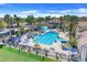 Aerial view of a large community pool with palm trees, lounge chairs, and umbrella-covered tables at 1950 Windward Oaks Ct, Kissimmee, FL 34746