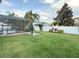 A backyard area with grass and a white pergola leading to a screened-in pool area at 2121 Knollview Ct, Oviedo, FL 32765