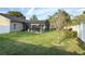 Landscaped backyard with a green lawn, perimeter fence, and screened-in pool area at 2121 Knollview Ct, Oviedo, FL 32765