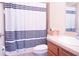 Well-lit bathroom features a shower-tub combo with horizontally-striped shower curtain at 2608 Sunset Cir, Lake Wales, FL 33898