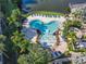 Aerial view of community pool area with splash zone, surrounded by tropical plants and lounge chairs at 3002 Bonfire Beach Dr # 202, Kissimmee, FL 34746